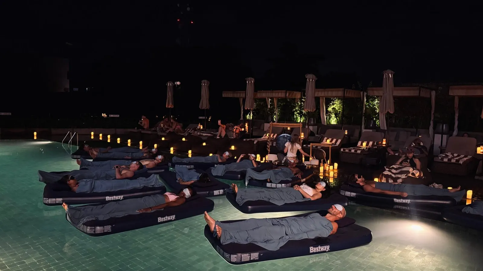 Guests floating on mats during a sound healing session in the pool at Reload Sanctuary Canggu