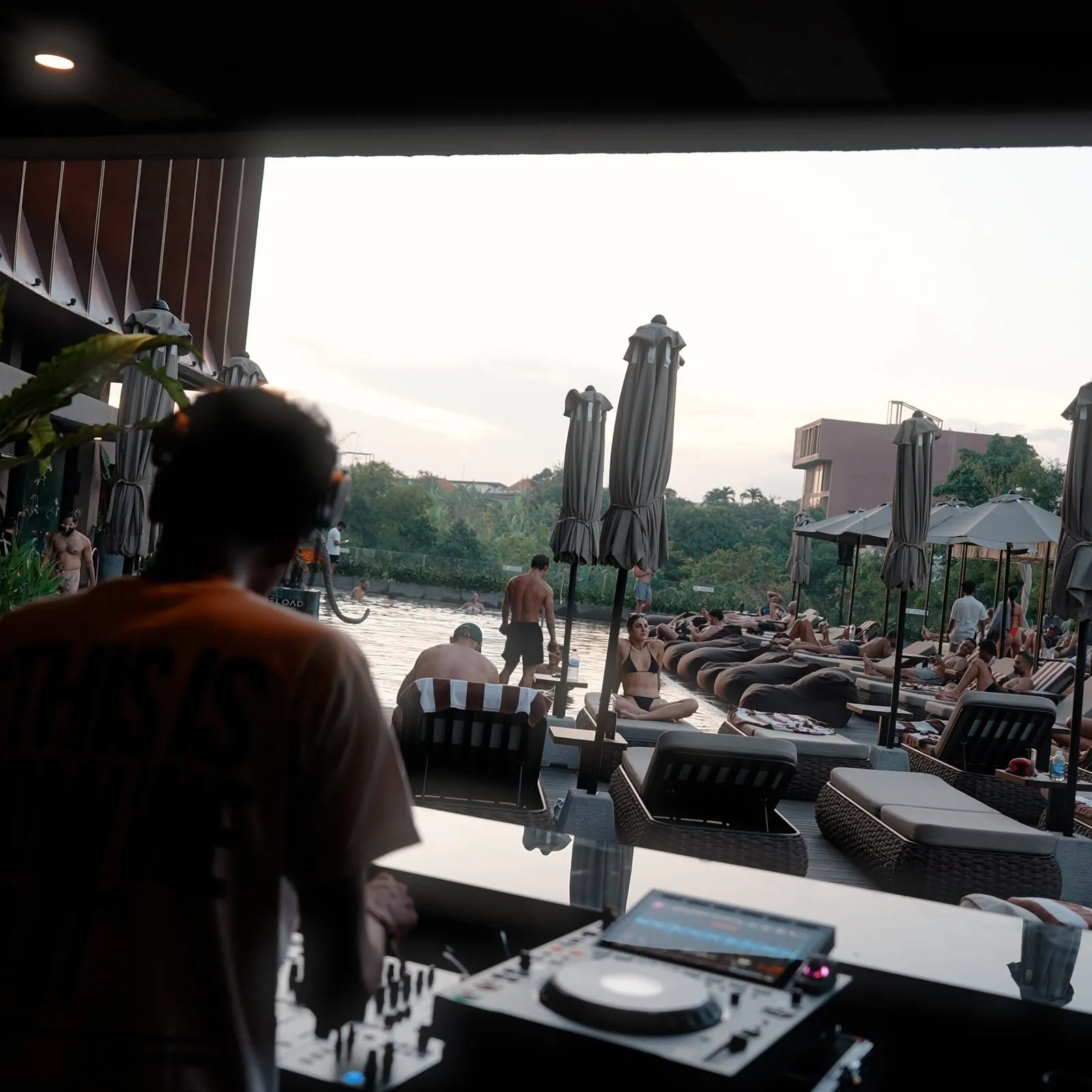 Resident DJ playing Afro House at sunset on the pool deck at Reload Sanctuary Bali